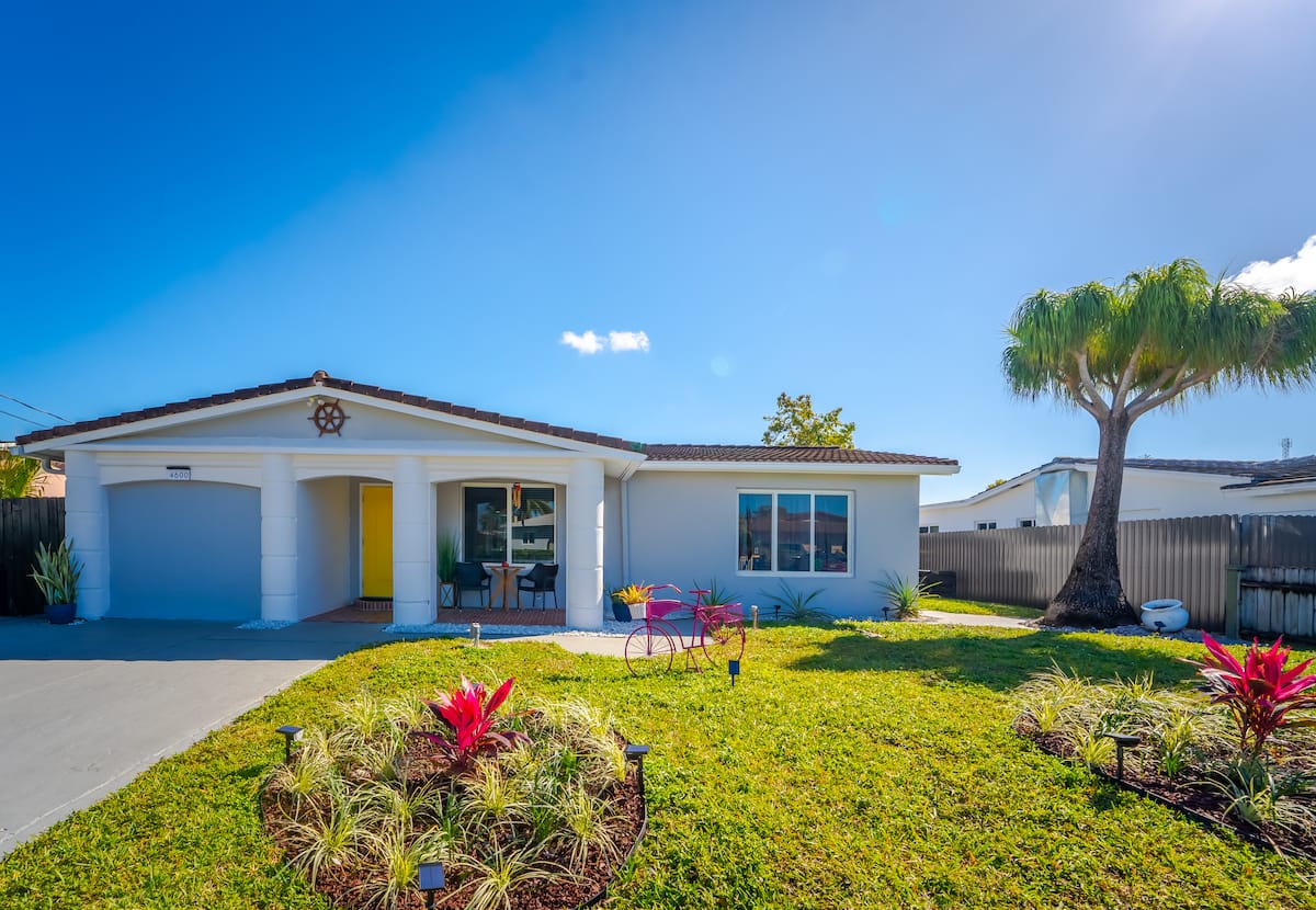 White home with a yellow front door and palm tree
